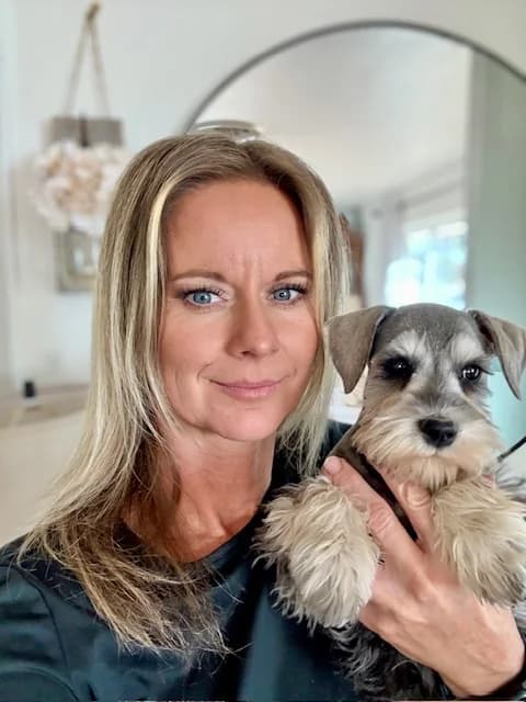 A woman holding a miniature schnauzer puppy