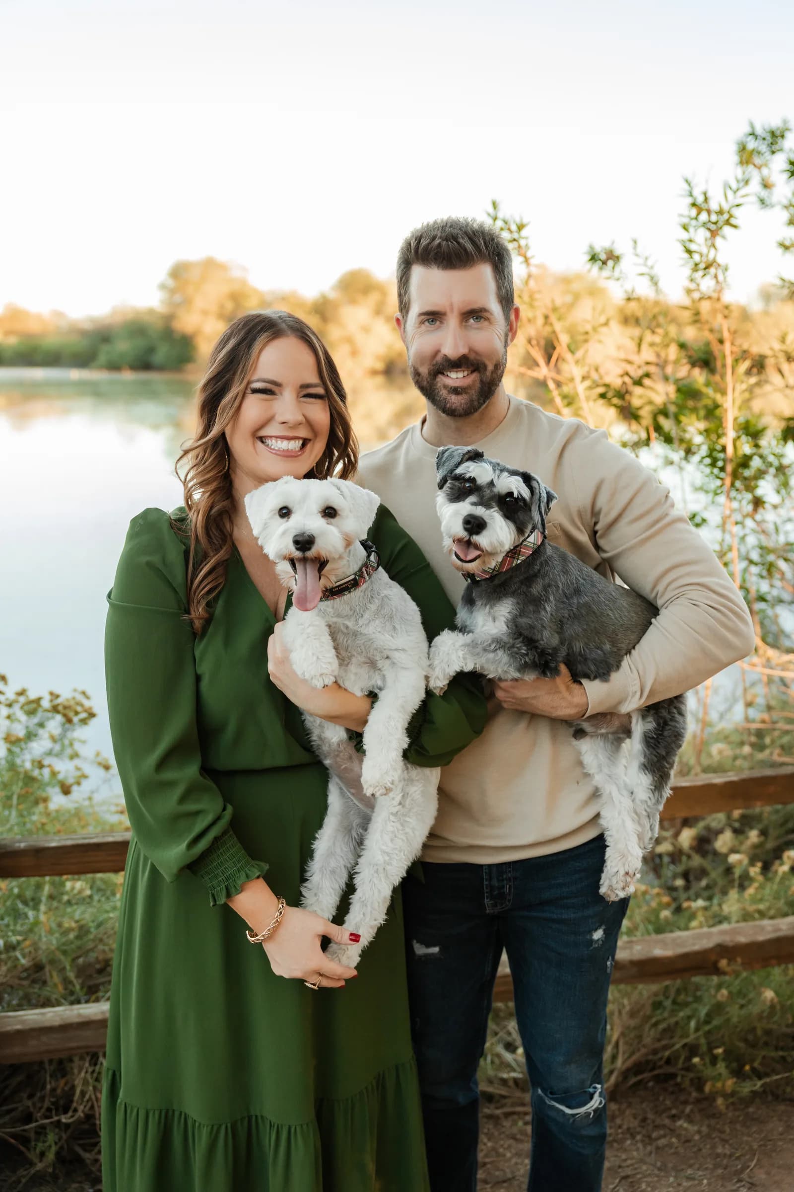A couple by the water holding their white and salt and pepper miniature schnauzers