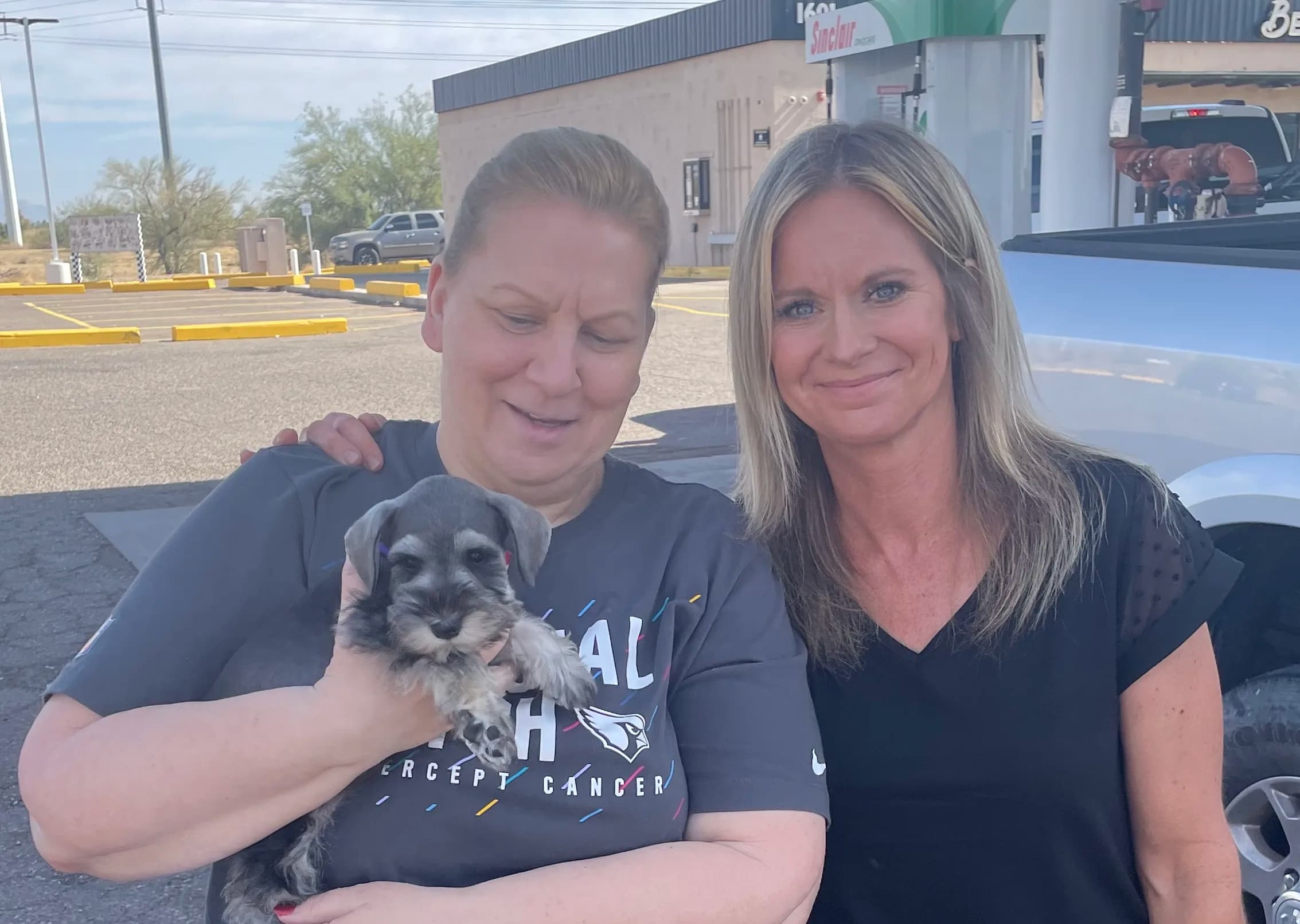 Two women holding a miniature schnauzer puppy